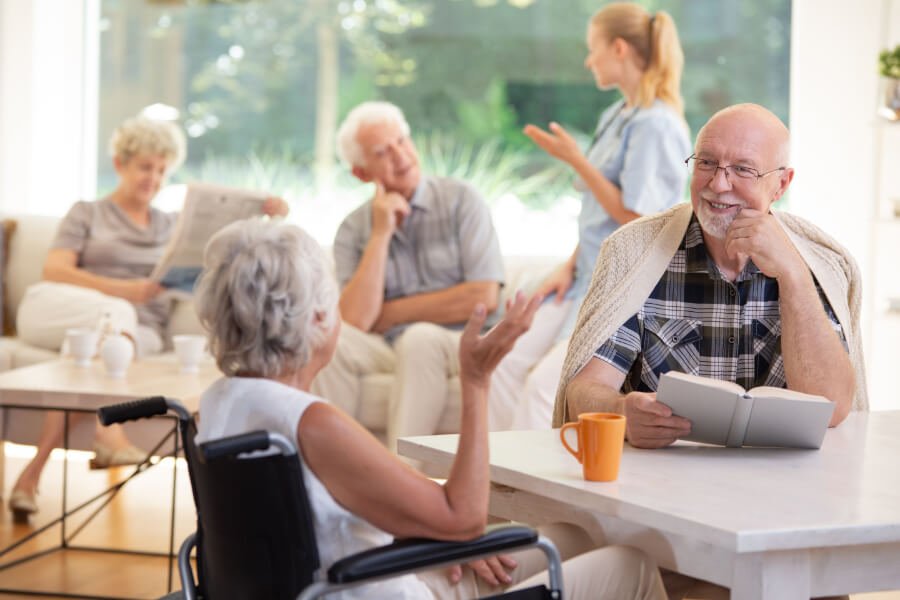 smiling-senior-man-with-book-talking-with-elderly-JNZQ9K2.jpg